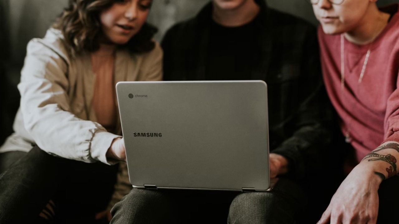 Three people using a Chromebook.