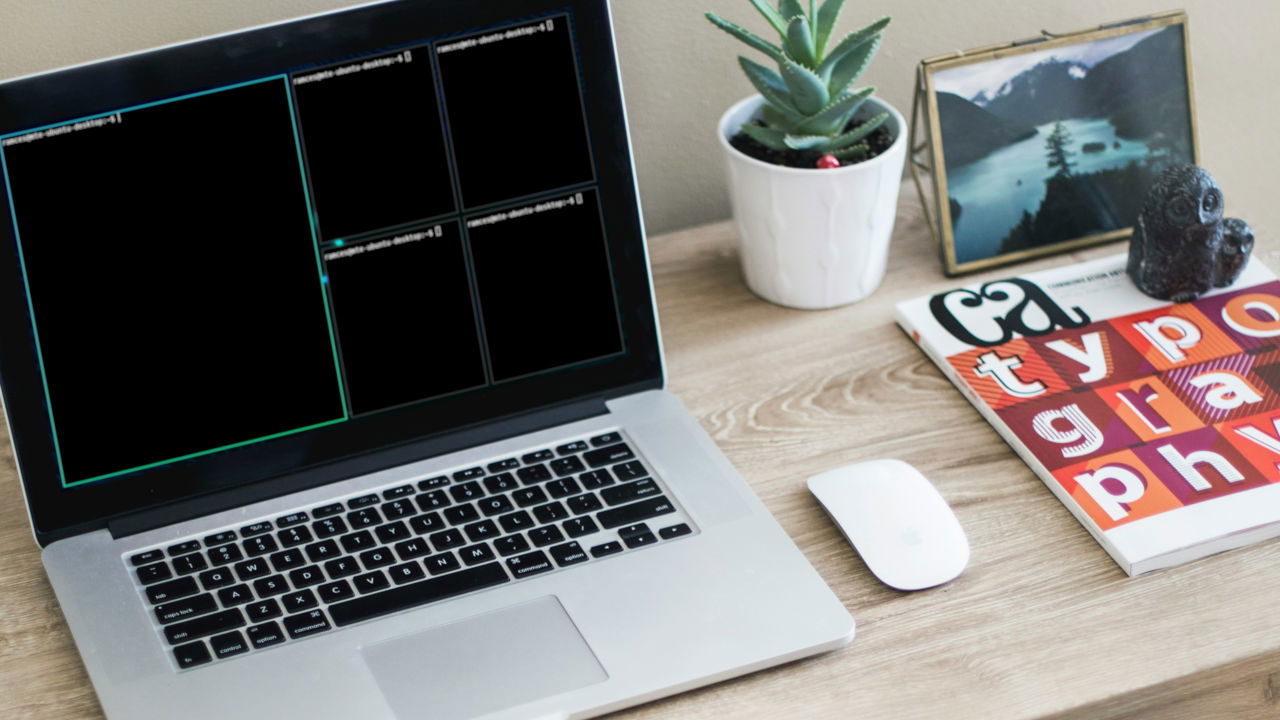 A photograph of a laptop on top of a simple desk.