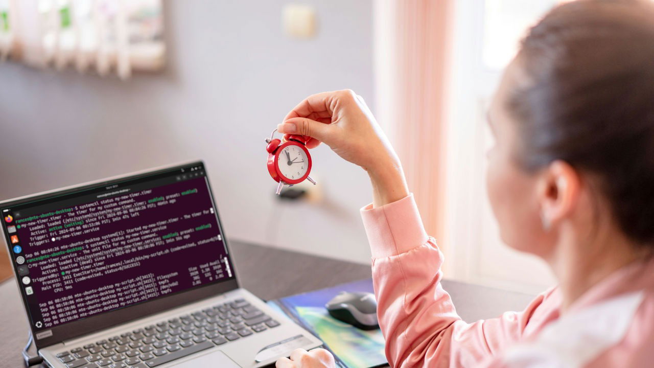 A photograph of a woman holding an alarm clock while in front of a laptop.